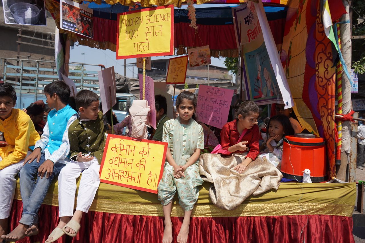 about-01 Children adorned in traditional attire sit on a colorful Indian parade float.