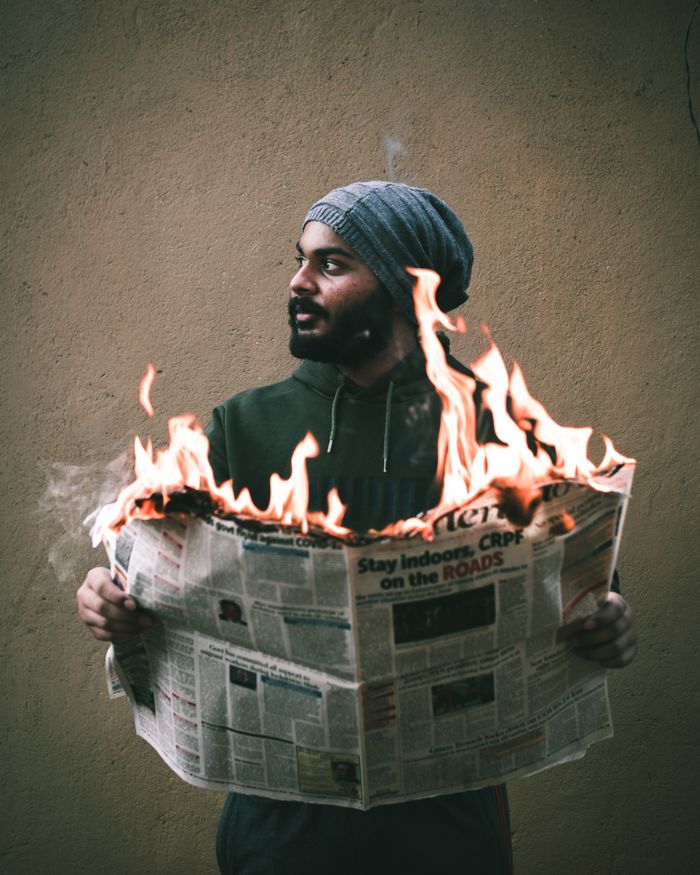 gallery-1 Thoughtful Arabian male holding newspaper with bright flashes of fire and looking away